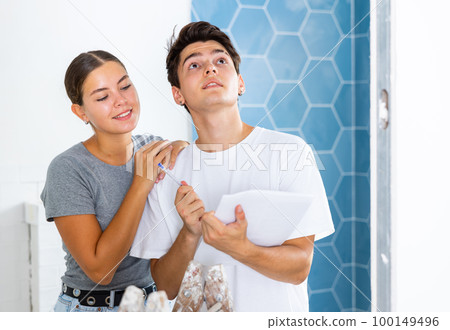Young couple with documents checks the number of tiles, making important notes Young couple with documents checks the number of tiles, making important notes 100149496