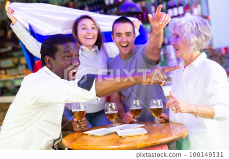 Happy multiracial friends football fans holding the flag of Russia, enjoing game and beer in the bar 100149531