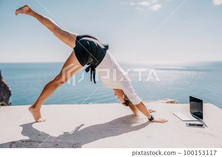 Woman sea laptop yoga. Business woman freelancer in yoga pose working over blue sea beach at laptop and meditates. Girl relieves stress from work. Freelance, digital nomad, travel and holidays concept 100153117