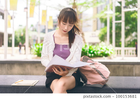 Young adult asian student woman sit and studying with notebook at campus area. Young adult asian student woman sit and studying with notebook at campus area. 100153681
