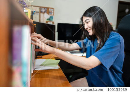 Young adult asian woman stay at home and selected a book for relax time at workplace Young adult asian woman stay at home and selected a book for relax time at workplace 100153989