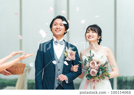 Guests celebrating with the bride and groom taking a flower shower at a wedding Guests celebrating with the bride and groom taking a flower shower at a wedding 100154068