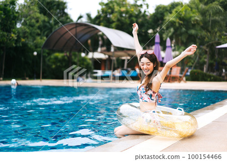 Happy young asian woman relax on summer holiday at pool villa. 100154466