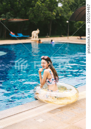 Beautiful girl hush hand gesture with bikini and inflatable beside pool at Pattaya, Thailand. 100154467