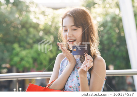Young adult asian woman holding credit card and shopping bags. Young adult asian woman holding credit card and shopping bags. 100154557