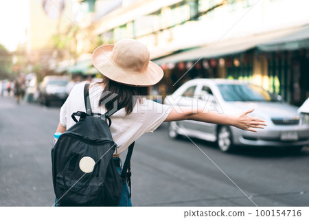 Back view of young asian traveller woman call a taxi for travel. 100154716