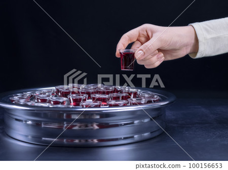 Closeup of young woman taking communion from small cups on black background Closeup of young woman taking communion from small cups on black background 100156653