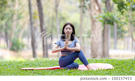 Asian woman doing yoga in nature in the forest, Meditation and breathing exercises, Treat ADHD and train your mind to be calm, Healthy exercise, Mindfulness, Homeopathy, Park yoga. 100157453