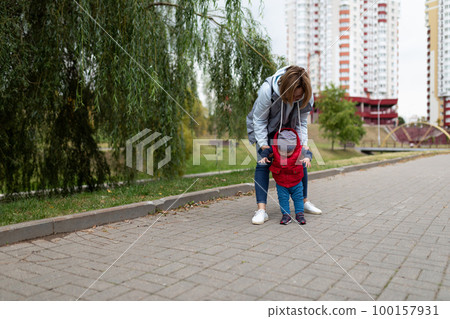 young mother walks with her little son in the park 100157931