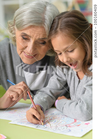 Portrait of grandmother and granddaughter drawing together 100160409