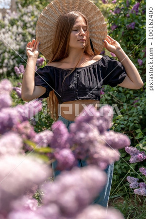 portrait of young woman with long hair outdoors in blooming lilac garden portrait of young woman with long hair outdoors in blooming lilac garden 100162400