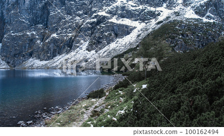 Czarny Staw pod Rysamy or Black Pond lake near the Morskie Oko Snowy Mountain Hut in Polish Tatry mountains, drone view, Zakopane, Poland. 4k Aerial view shot of beautiful green hills and mountains in Czarny Staw pod Rysamy or Black Pond lake near the Morskie Oko Snowy Mountain Hut in Polish Tatry mountains, drone view, Zakopane, Poland. 4k Aerial view shot of beautiful green hills and mountains in 100162494