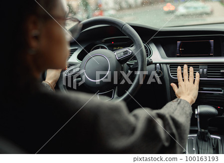 Female driver is controlling car air conditioning system grid panel on console while driving in city Female driver is controlling car air conditioning system grid panel on console while driving in city 100163193