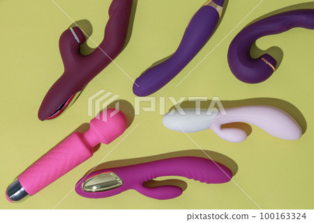A lot of different dildo vibrators on yellow background with shadows. Sex toy for adult 100163324
