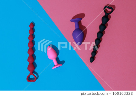 Top view of buttplugs and dildos for anal sex on colored background with shadows. Sex shop concept Top view of buttplugs and dildos for anal sex on colored background with shadows. Sex shop concept 100163328