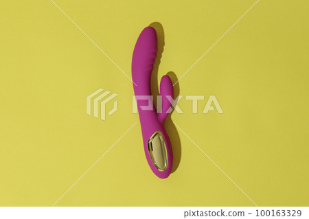 Top view of pink dildo vibrator on yellow background with shadows. Sex toy for adult Top view of pink dildo vibrator on yellow background with shadows. Sex toy for adult 100163329