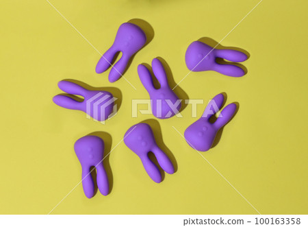 Top view of many violet dildo vibrators for clitoris on yellow background. Sex toys for adult 100163358