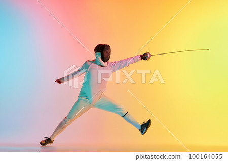 Long attack. Young man, male fencer with sword practicing in fencing over gradient pink-yellow background in neon light. Sportsman shows fencing technique 100164055