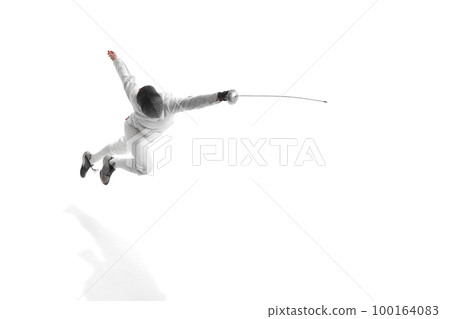Professional male fencer in fencing costume training with sword isolated on white studio background. Concept of sport, competition, professional skills, achievements 100164083