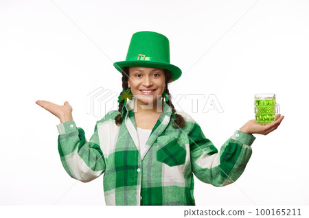 Multi-ethnic brunette woman, charming waitress dressed in carnival clothes for St. Patrick's Day, smiling looking at camera, holding a mug with Irish green beer and a copy space on her hands palms up Multi-ethnic brunette woman, charming waitress dressed in carnival clothes for St. Patrick's Day, smiling looking at camera, holding a mug with Irish green beer and a copy space on her hands palms up 100165211