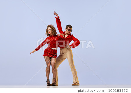 Young beautiful couple of dancers in bright retro fashion clothes, stage costumes dancing over lilac color background. Concept of music, art, dance, retro Young beautiful couple of dancers in bright retro fashion clothes, stage costumes dancing over lilac color background. Concept of music, art, dance, retro 100165552