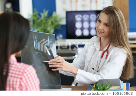 Female patient and doctor with spine x-ray scan meet in hospital Female patient and doctor with spine x-ray scan meet in hospital 100165968