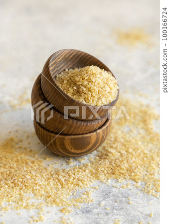 Wooden bowls with Dry uncooked bulgur wheat grain close up, copy space. Healthy food Wooden bowls with Dry uncooked bulgur wheat grain close up, copy space. Healthy food 100166724