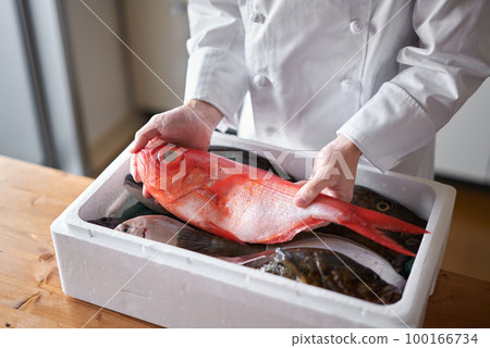 A chef picking up the fish delivered from the production area 100166734