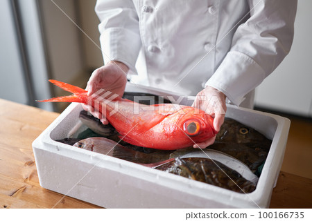 A chef picking up the fish delivered from the production area 100166735