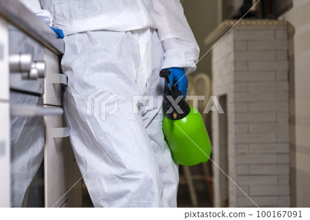 An exterminator in work clothes sprays pesticides with a spray gun. Fight against insects in apartments and houses. Disinsection of the premises An exterminator in work clothes sprays pesticides with a spray gun. Fight against insects in apartments and houses. Disinsection of the premises 100167091