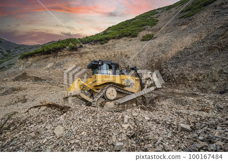 Yellow excavator on new construction site, with the bright sun and nice red sky in the background 100167484