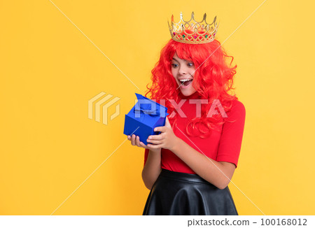surprised child in crown with present box on yellow background surprised child in crown with present box on yellow background 100168012