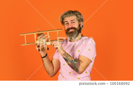 travel by plane. dream about summer vacation. mature pilot orange background. aeromodelling. handmade toy shop. lets fly. feel the freedom. happy carpenter. bearded man play with wooden plane travel by plane. dream about summer vacation. mature pilot orange background. aeromodelling. handmade toy shop. lets fly. feel the freedom. happy carpenter. bearded man play with wooden plane 100168092