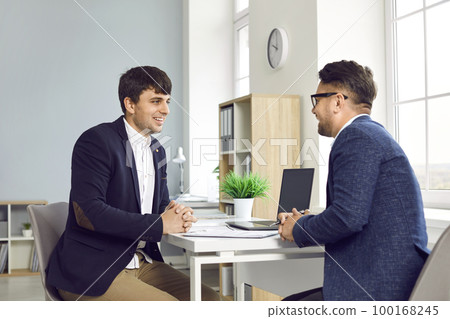 Two happy smiling young business people talking during their meeting in the office 100168245