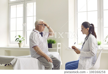 Senior man patient complaining on headache to attentive woman doctor in modern clinic hospital. Senior man patient complaining on headache to attentive woman doctor in modern clinic hospital. 100168258