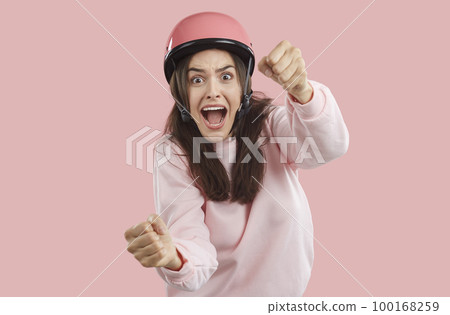 Scared brunette woman imagines she is driving car and holding steering wheel on pink background. Scared brunette woman imagines she is driving car and holding steering wheel on pink background. 100168259