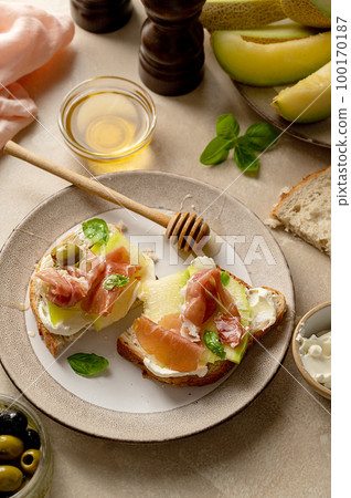Melon with prosciutto toast with basil and honey. Antipasti snack. Melon with prosciutto toast with basil and honey. Antipasti snack. 100170187