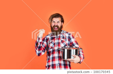 Just for fun. Enameled cast iron cooking vessels. Nonstick pan coated polytetrafluoroethylene teflon. Cooking healthy food. Professional chef man cook in checkered shirt. bearded husband. Restaurant 100170345