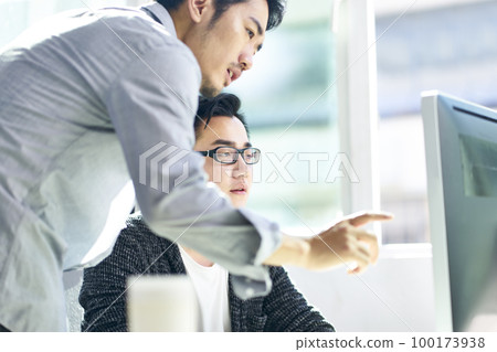 two young asian corporate executives working together using desktop computer two young asian corporate executives working together using desktop computer 100173938