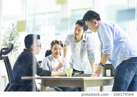 group of four asian teammates working together discussing business in office 100174564