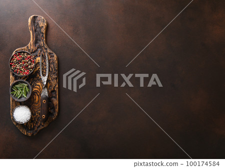 Chopping board with salt,pepper and rosemary with barbeque steel fork on brown Chopping board with salt,pepper and rosemary with barbeque steel fork on brown 100174584