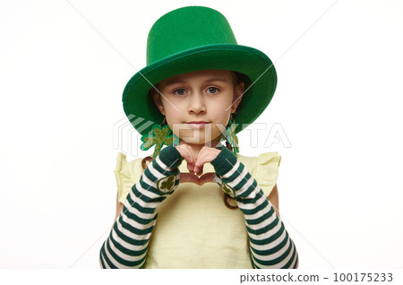 Adorable Irish little child girl, dressed as Leprechaun in green carnival wear for St Patrick's Day, showing a heart shape from fingers, isolated on white background. Ireland's culture and traditions Adorable Irish little child girl, dressed as Leprechaun in green carnival wear for St Patrick's Day, showing a heart shape from fingers, isolated on white background. Ireland's culture and traditions 100175233