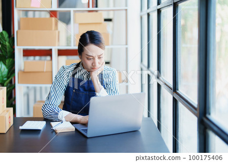 Starting small business entrepreneur of independent Asian woman showing her face worried about the sales of her business not reaching the target set. SME concepts. 100175406