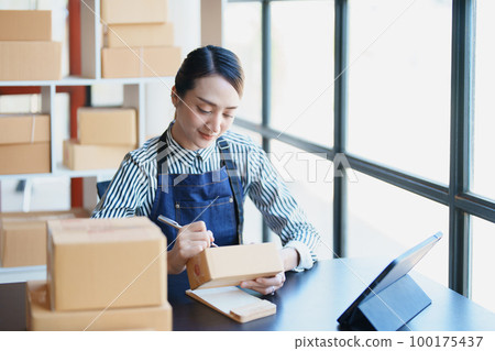 Starting small business entrepreneur of independent Asian female online seller packing products to send to customers and SME delivery concept. Starting small business entrepreneur of independent Asian female online seller packing products to send to customers and SME delivery concept. 100175437