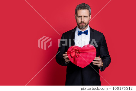 man holding gift for proposal at valentine day, copy space. tuxedo man man holding gift for proposal at valentine day, copy space. tuxedo man 100175512