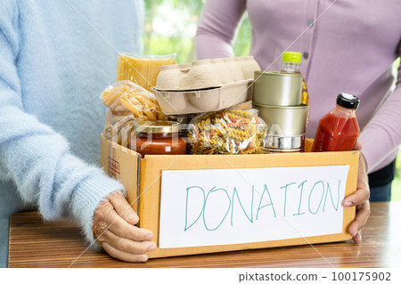Volunteers putting various dry food in donation box for help people. 100175902