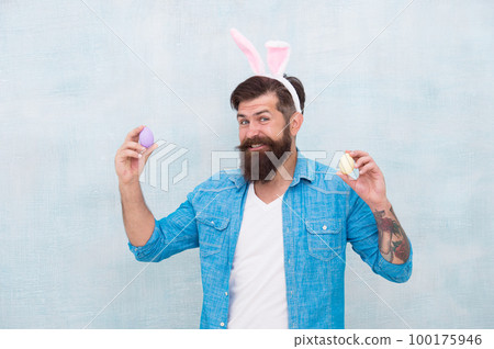 Celebration of spring holiday. Bearded man bunny ears and Easter eggs. Everything you need for Easter is here. Hipster long ears holding egg. Culture customs and traditions. Easter bunny colored eggs 100175946