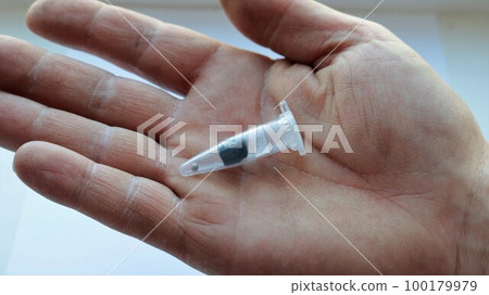 small transparent plastic container with one seed lying on a rough male palm close-up, cannabis seed for home cultivation in a closed protective capsule in a human hand small transparent plastic container with one seed lying on a rough male palm close-up, cannabis seed for home cultivation in a closed protective capsule in a human hand 100179979