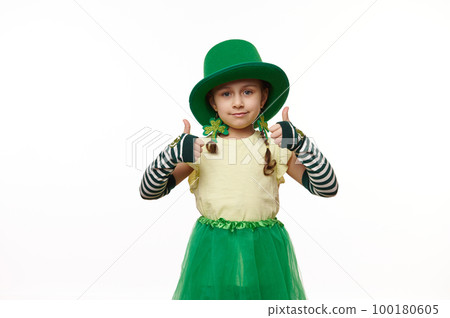 Lovely little Leprechaun girl dressed in carnival costume, stripped gloves, green hat, skirt and clover leaf earrings, thumbs up looking at camera, on isolated white background. Saint Patrick's Day Lovely little Leprechaun girl dressed in carnival costume, stripped gloves, green hat, skirt and clover leaf earrings, thumbs up looking at camera, on isolated white background. Saint Patrick's Day 100180605