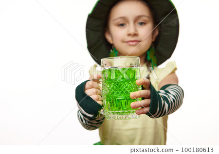 Selective focus on a mug with green drink in the hands of a blurred little leprechaun girl on white background. St Patrick's Day Selective focus on a mug with green drink in the hands of a blurred little leprechaun girl on white background. St Patrick's Day 100180613